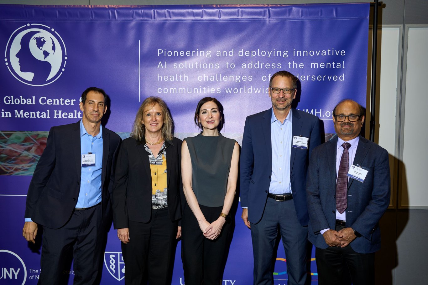 Five people pose for a photo in front of a GCAIMH Annual Summit banner.
