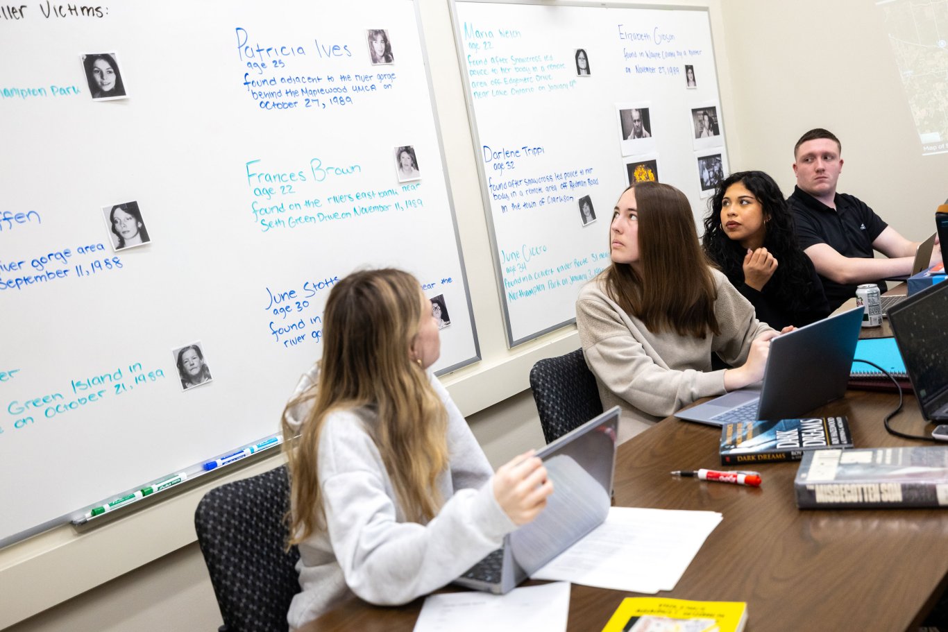 An image of three students looking at information on a white board.