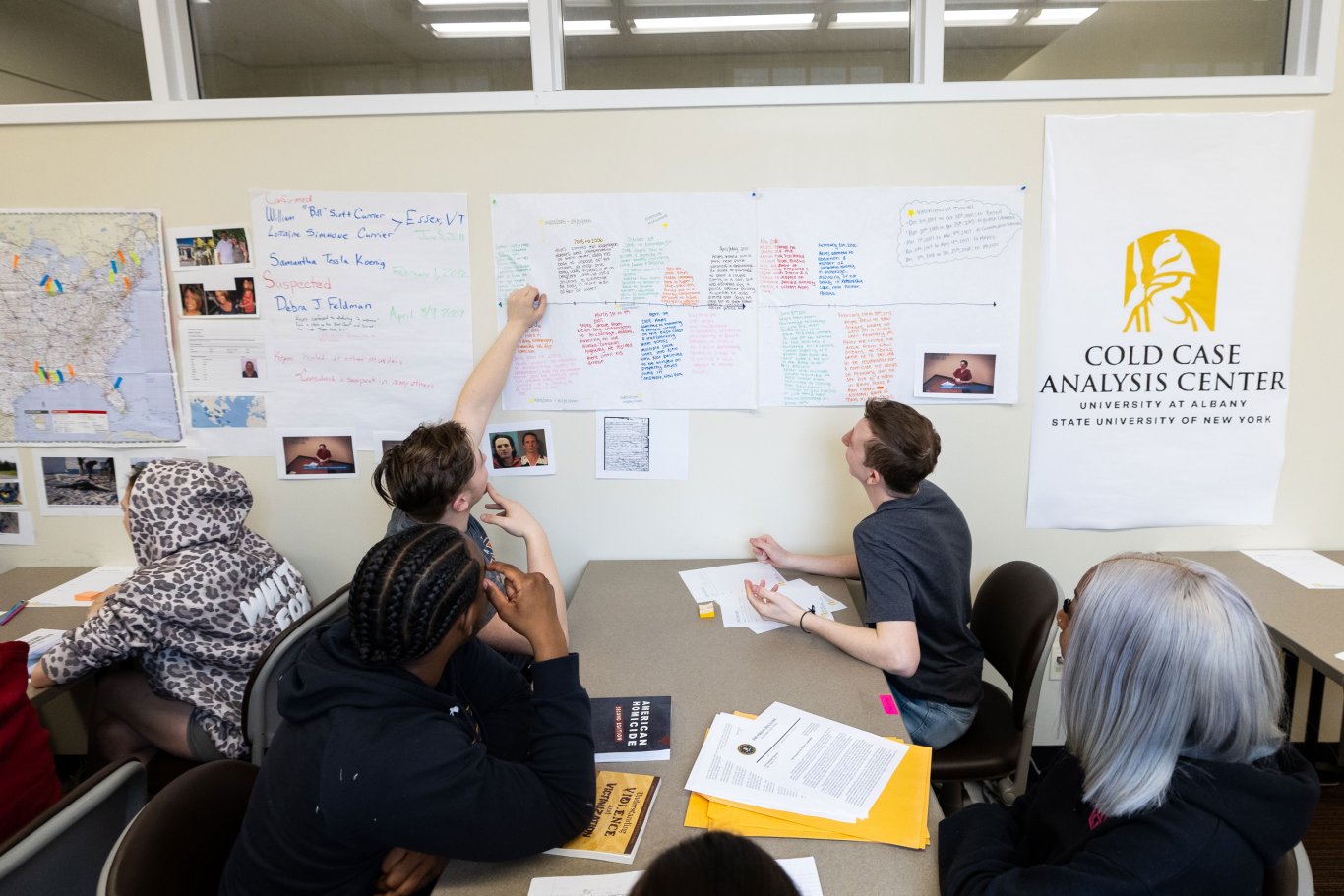 An image of three students looking at information on a white board.