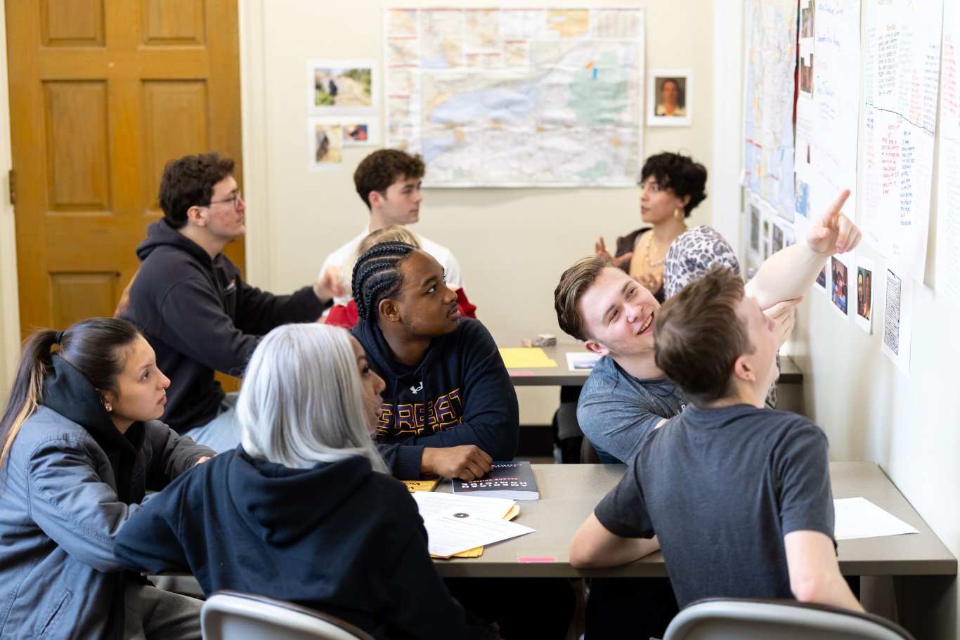 An image of four students looking up at information on a white board.