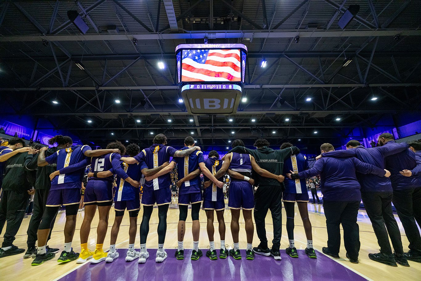 UAlbany basketball players lined up with their arms around each other before the Big Purple Growl Game.