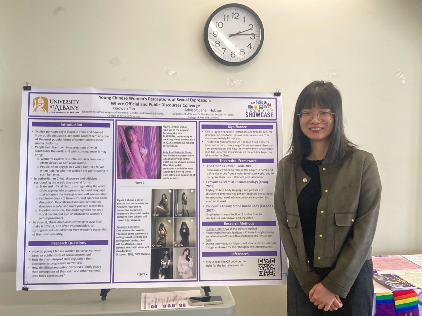 A student standing next to their poster project.
