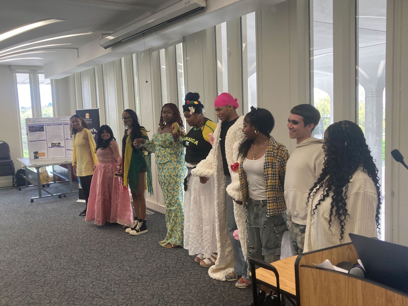 Nine students holding hands standing next to each other.