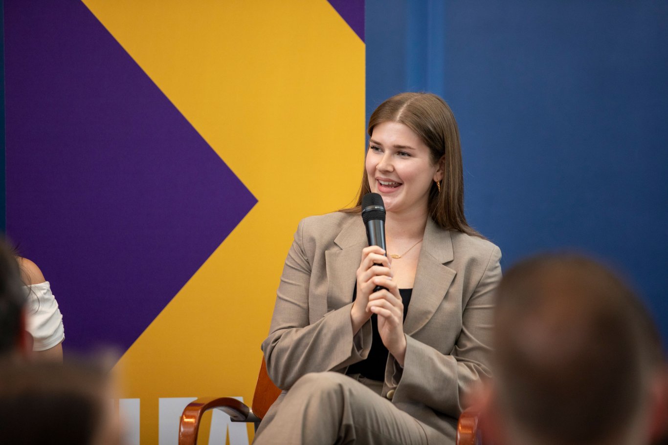 A student presenter smiles and speaks into handheld microphone during a Showcase panel presentation.