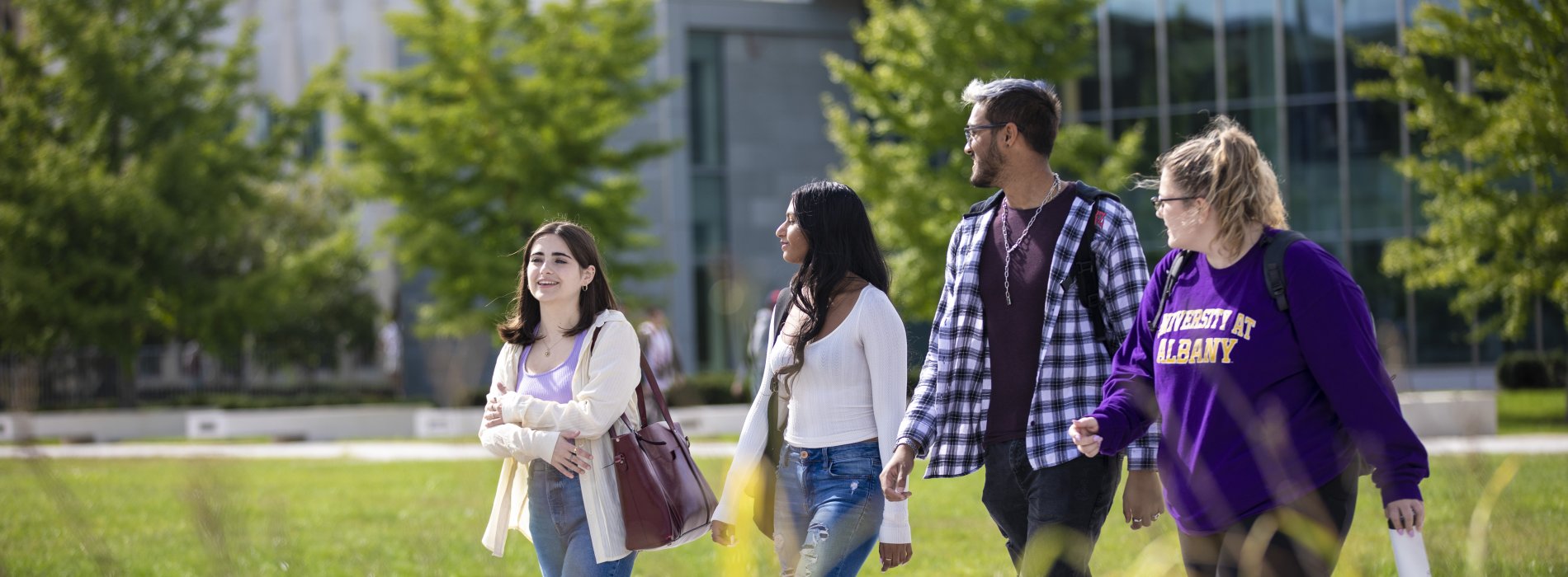 UAlbany students walk in a group together on campus during a beautiful sunny day