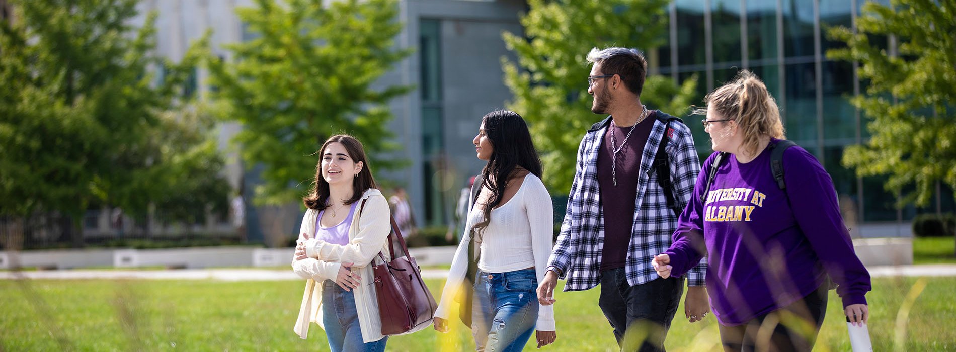 UAlbany students walk in a group together on campus during a beautiful sunny day