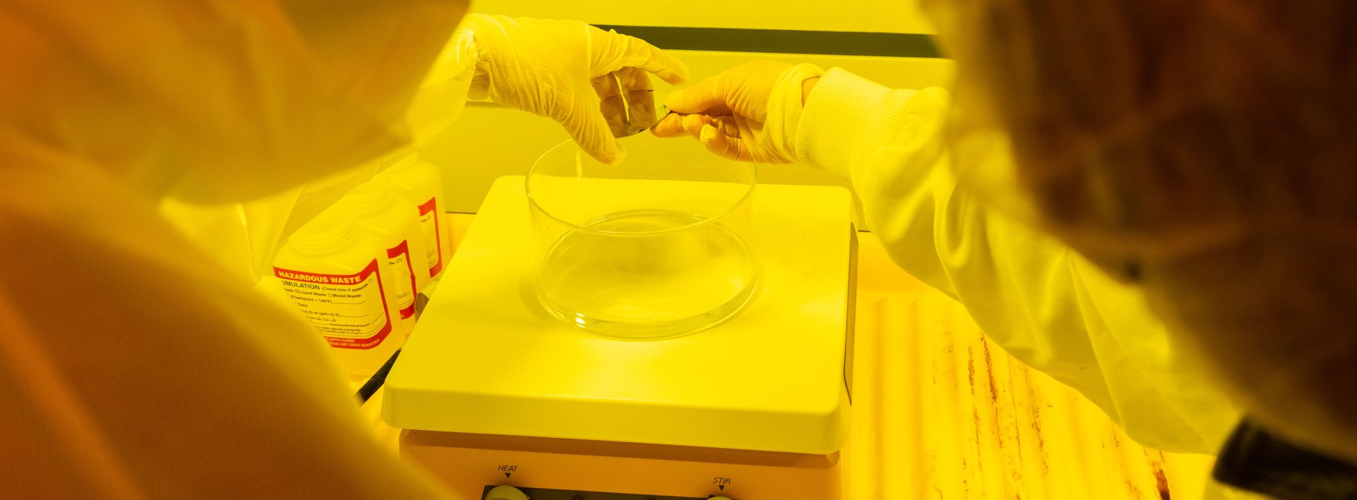 Two individuals in white lab coats participate in a cleanroom tour as part of the University at Albany's semiconductor program.