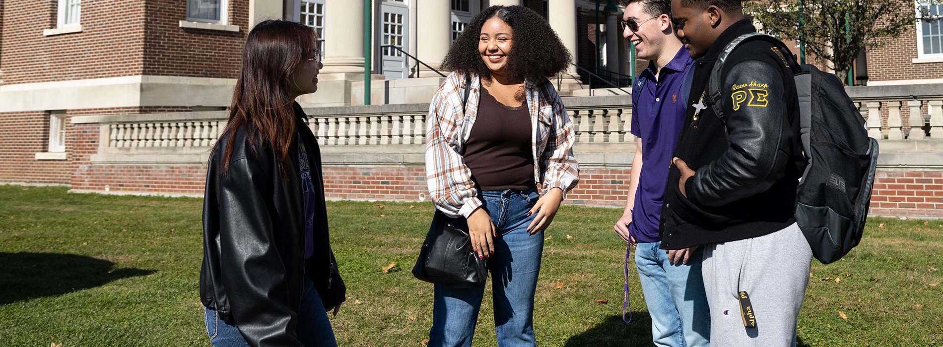 Four students talking outside in front of a building on UAlbany's Downtown Campus.