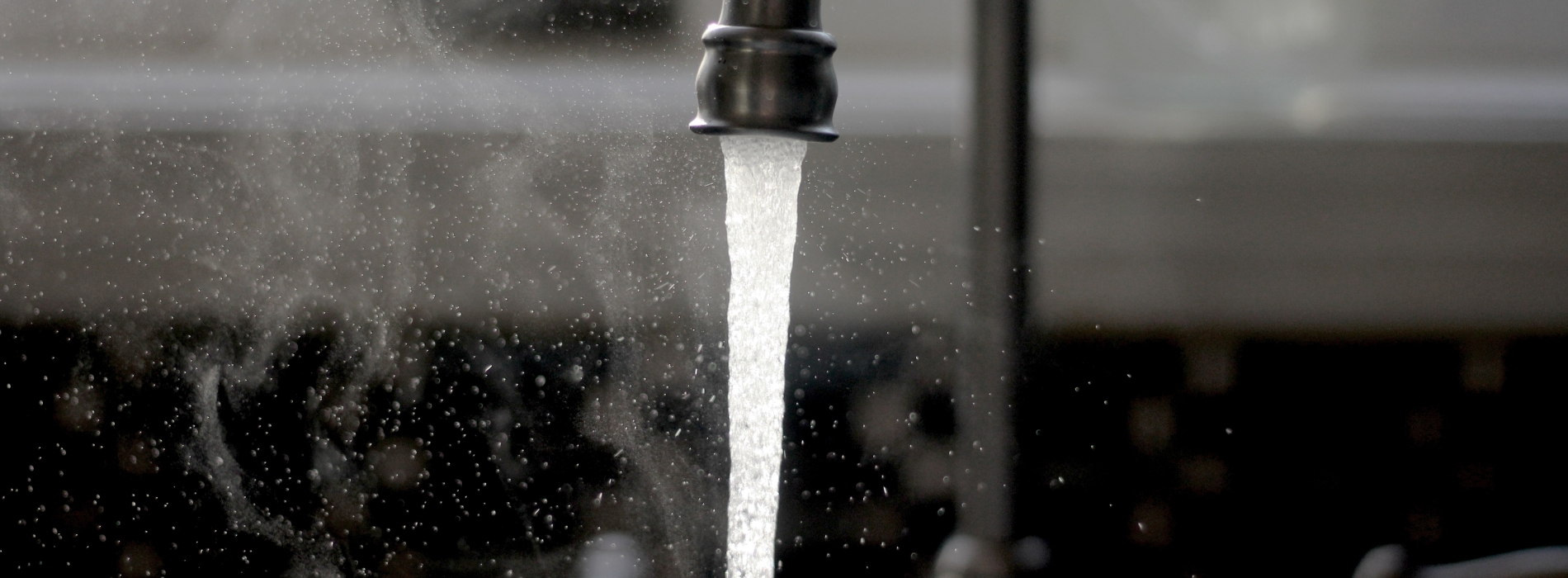 Close up of kitchen faucet with a strong stream of water