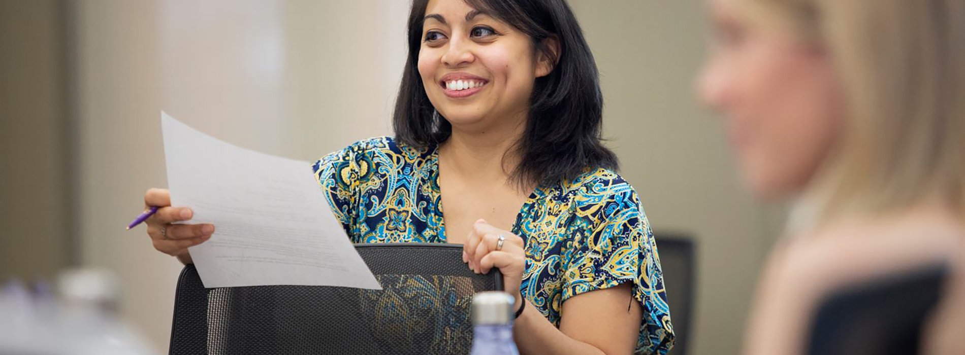 Woman smiling holding a paper in class.