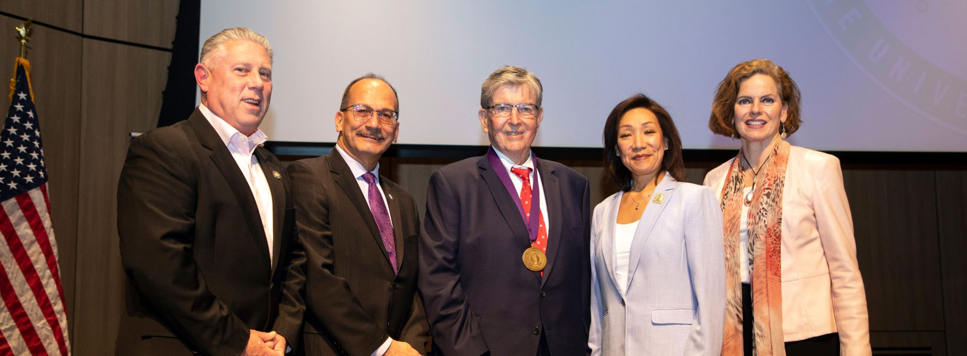 State Assemblymember John T. McDonald III, UAlbany President Havidán Rodríguez, State Senator Neil D. Breslin, UAlbany Provost Carol Kim and State Assemblymember Patricia A. Fahy pose for a photo indoors.