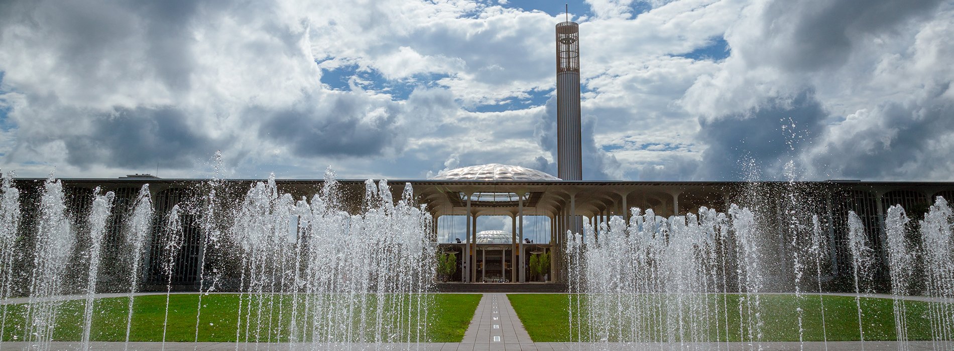 Fountains flow on campus in front of the UAlbany Academic Podium on a cloudy day.