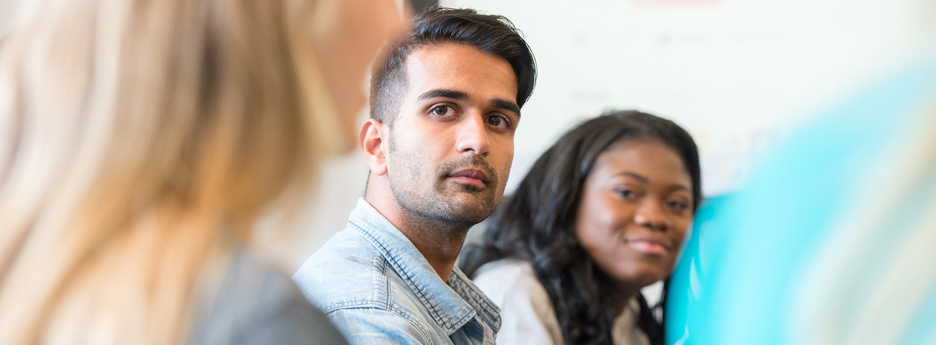 Three students are seen in profile interacting during class