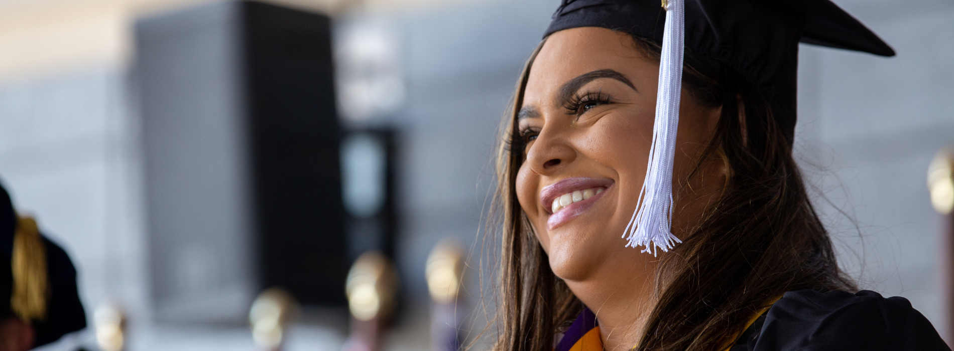 A graduate smiles wearing regalia.