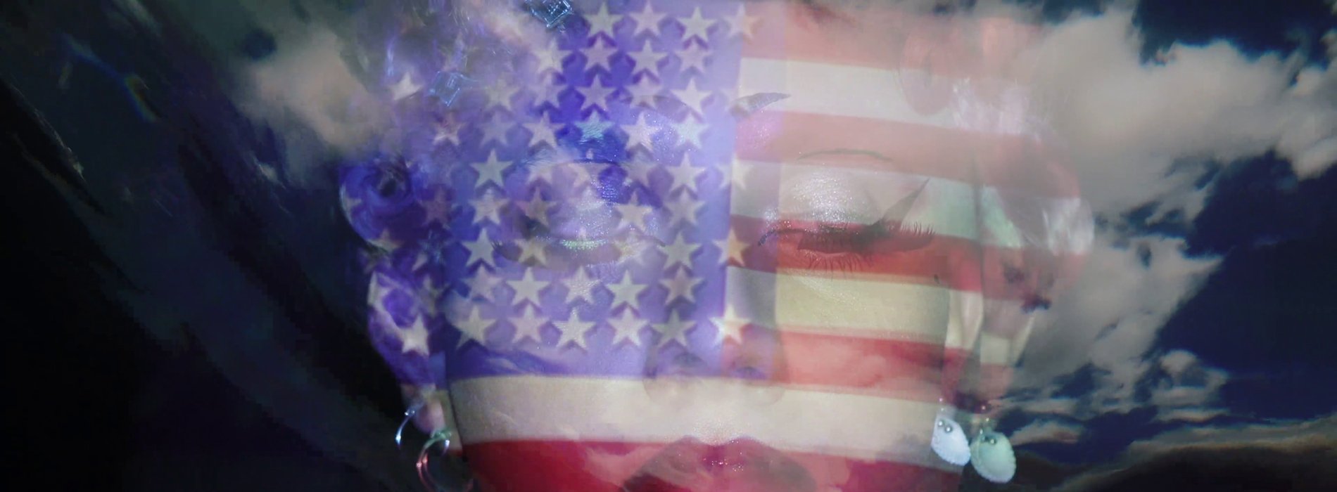 Drag performer with a projection of the US flag on their face