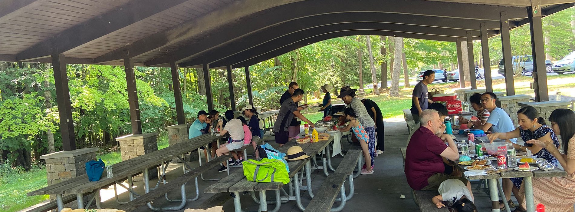 The UAlbany Asian Coalition of Professionals guests gathered at picnic table under pavilion