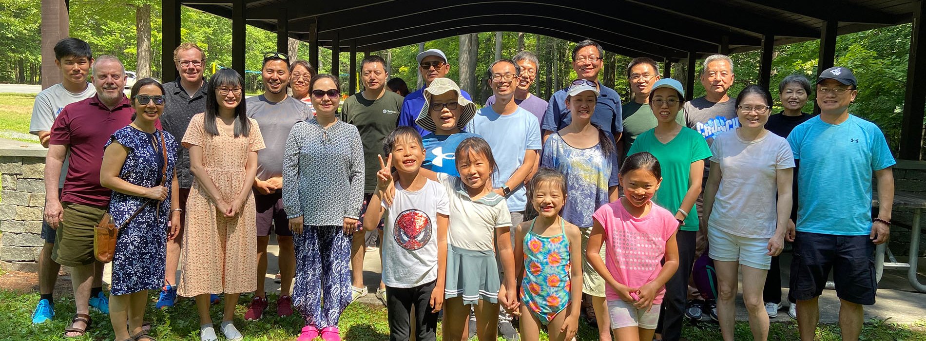 The UAlbany Asian Coalition of Professionals gather for a group photo in front of an outdoor pavilion