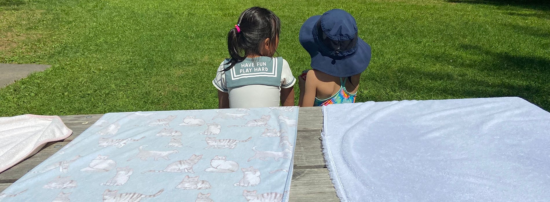 Two children are sitting together on a bench outside