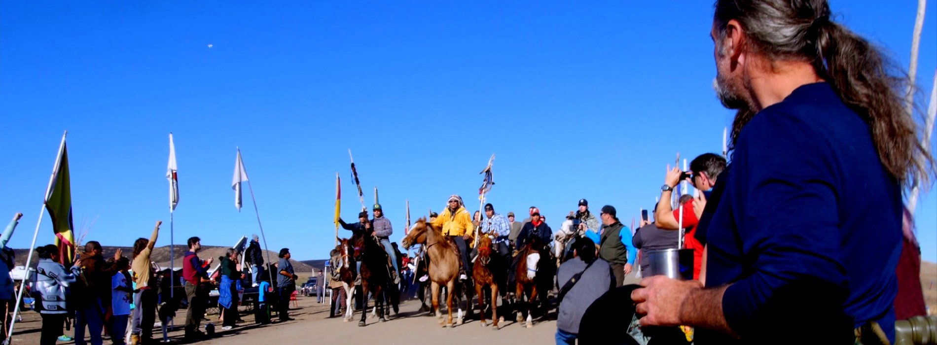 Indigenous activists on horseback in front of blue sky