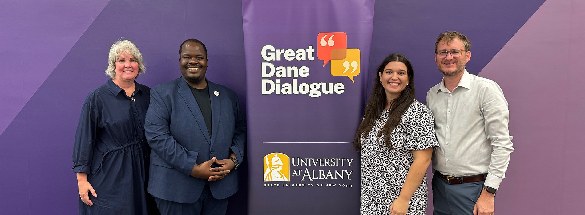 Four people standing next to a Great Dane Dialogue banner display.