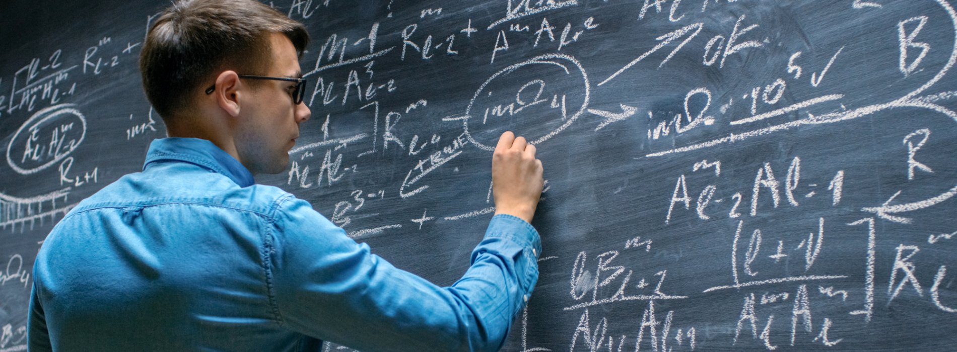 Student working on a mathematics formula at a chalkboard