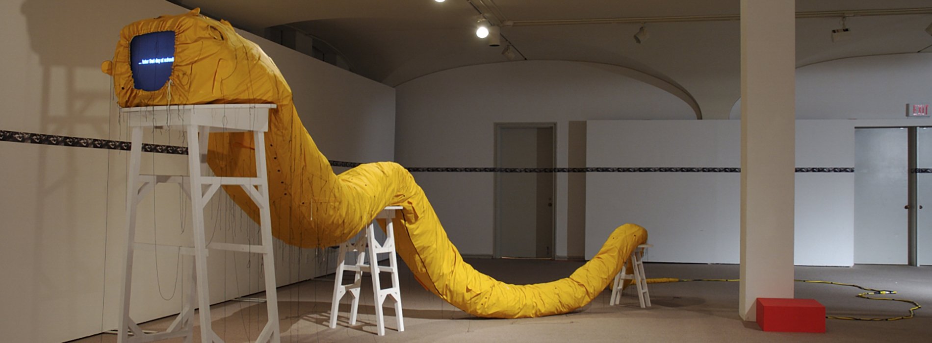 Pope L installation of a yellow snake sculpture
