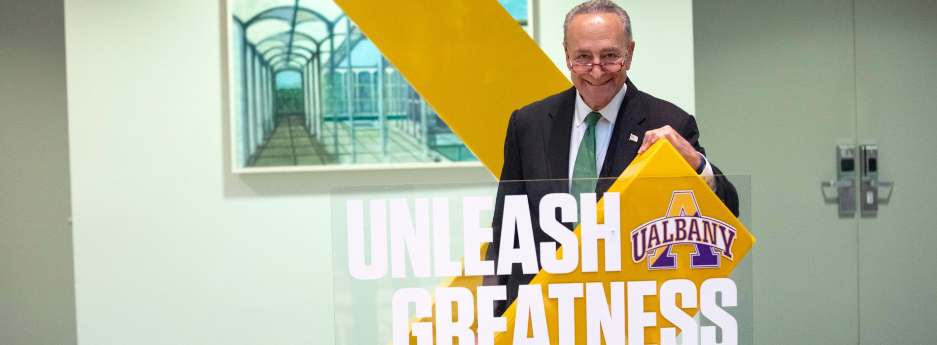 U.S. Senator Charles E. Schumer poses with an Unleash Greatness UAlbany sign.