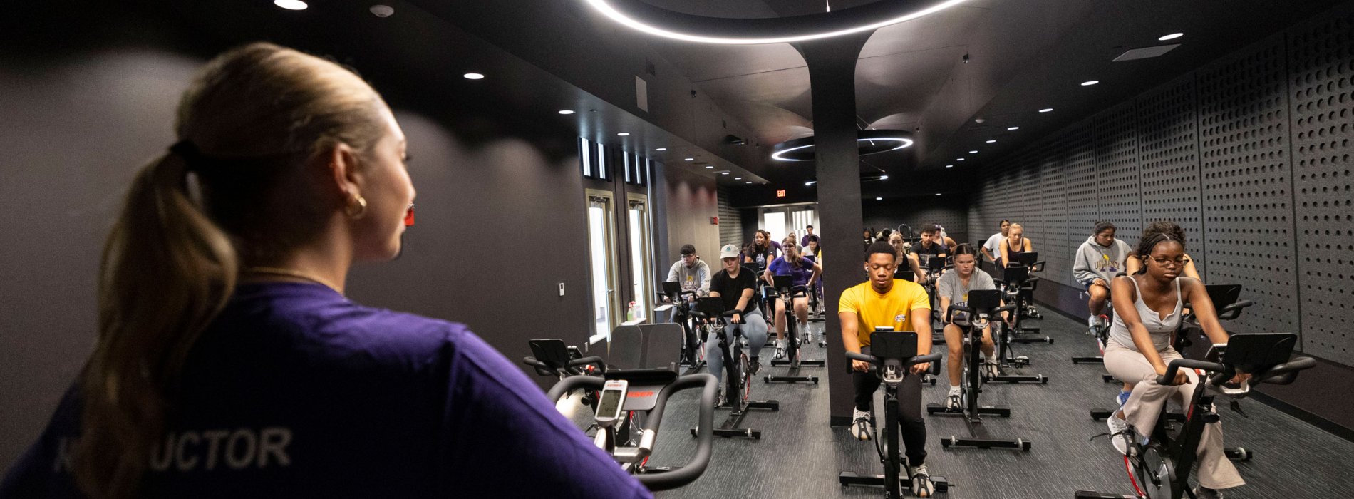 A group exercise instructor leads an indoor cycling class inside The Well at Colonial.