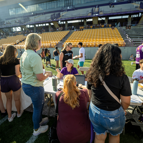UAlbany's Welcome Back Event, Great DANEtopia. A group of people appriach tables in order to talk to representative of various student organizations and activities on the lawn of Tom and Mary Casey Stadium.