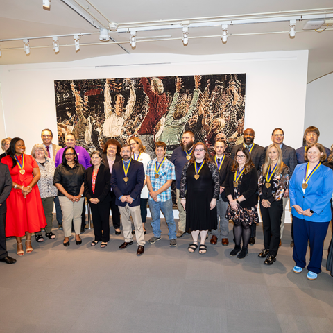 A group of attendees of the SUNY Chancellor's Award line up for a photo, standing and smiling together.