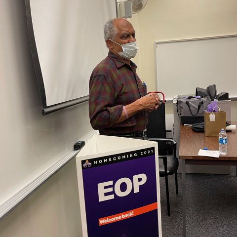 Dr. Harry Hamilton speaks in front of a whiteboard and EOP Homecoming 2021 sign.