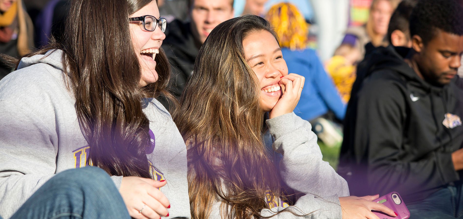 Two students sit together on a sunny homecoming day
