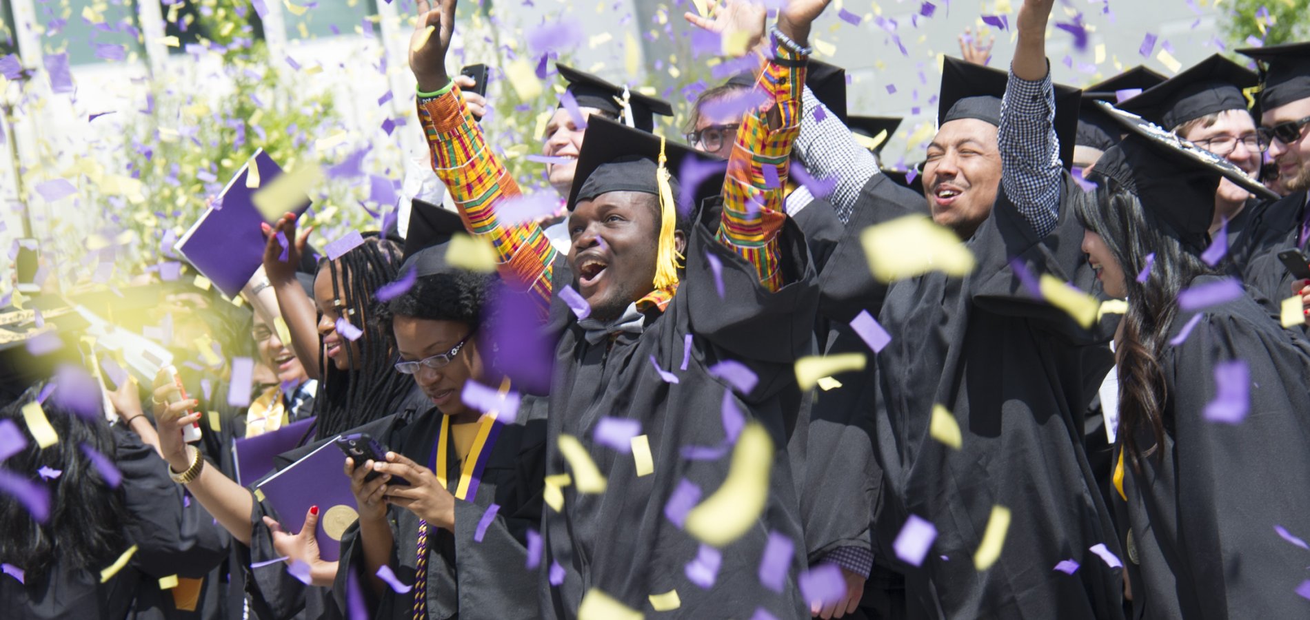 Graduates cheering as confetti falls at UAlbany Commencement.