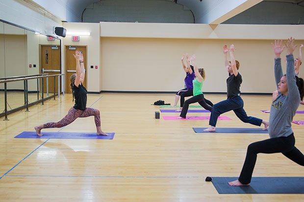 About a dozen students complete a yoga pose inside the Group Exercise Room.