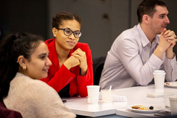 Three students are seated with breakfast items at a networking event