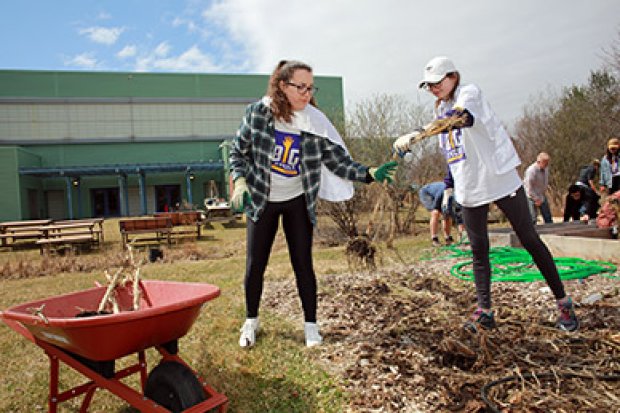 Two students clear a garden bed during a community service event
