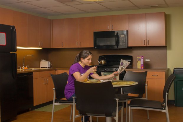 A student eats cereal and reads the newspaper inside a Liberty terrace apartment's kitchen.