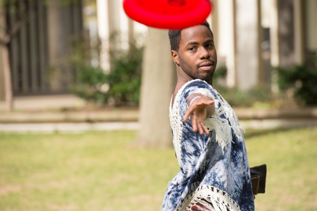 A student throws a frisbee in a grassy part of campus