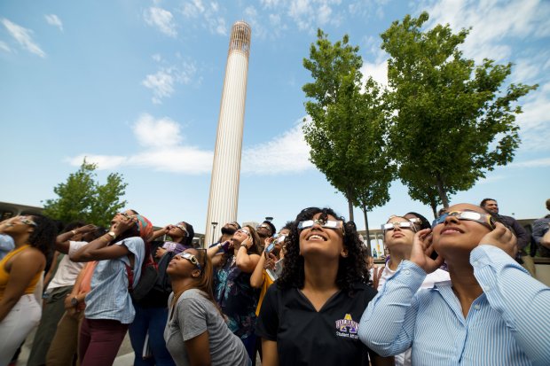 A crowd of people wearing eclipse glasses looks up at the sky under the UAlbany Carillon ahead of the 2017 solar eclipse.