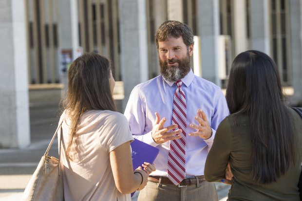 A profesor talking to two students on the main academicpodium of the University at Albany