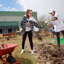 Two students clear a garden bed during a community service event