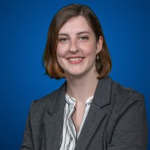 woman in suit jacket smiling with blue background