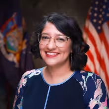 woman with glasses smiling with flags backdrop