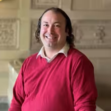 man in red sweater smiling indoors