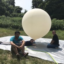 Maxim Coulliard holds a weather balloon outside beside two other researchers