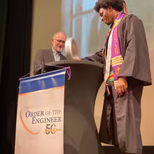 Department chair places ceremonial ring on the hand of graduating engineer. 