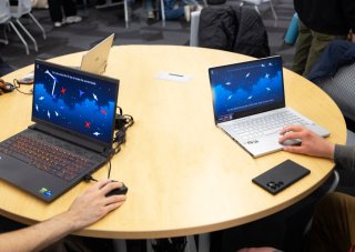 Students test games from laptops in a conference room at ETEC.