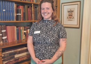 Tompkins stands in front of bookshelf at Seward House Museum