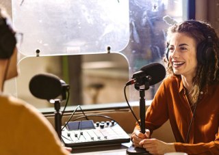 A podcast host interviews a guest in a recording studio.