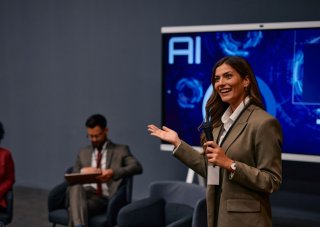 A public relations specialist answers questions at a press conference.